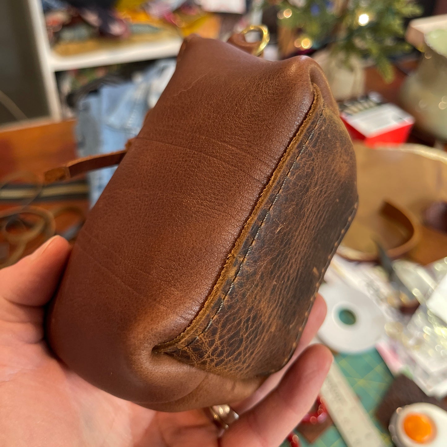 Brown leather pouch held in a hand with a blurred background