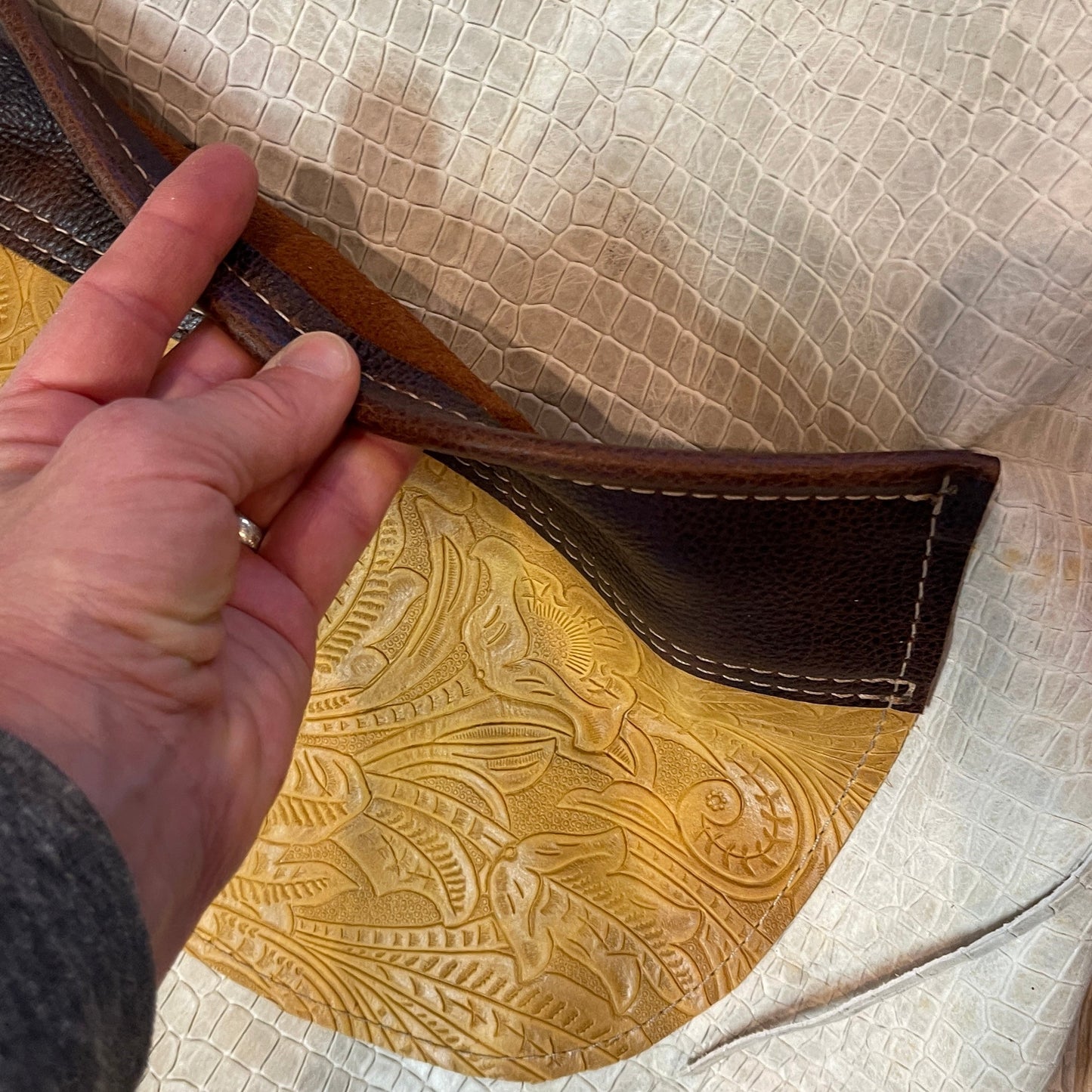 Close-up of a handbag with intricate leather work and fringe details.