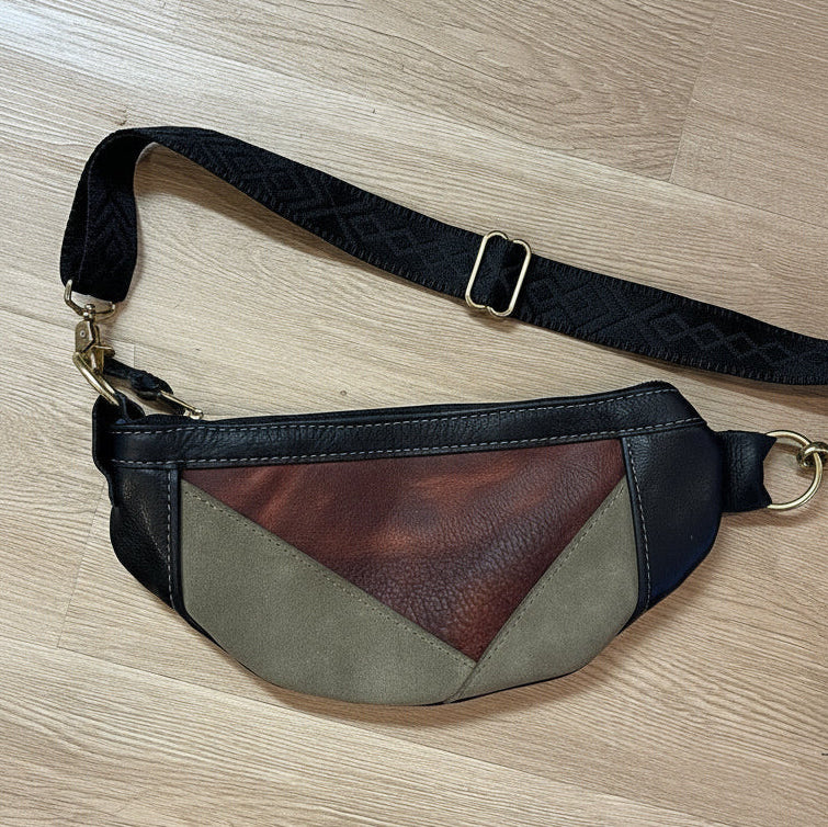 Multicolored waist bag with a black strap on a wooden surface