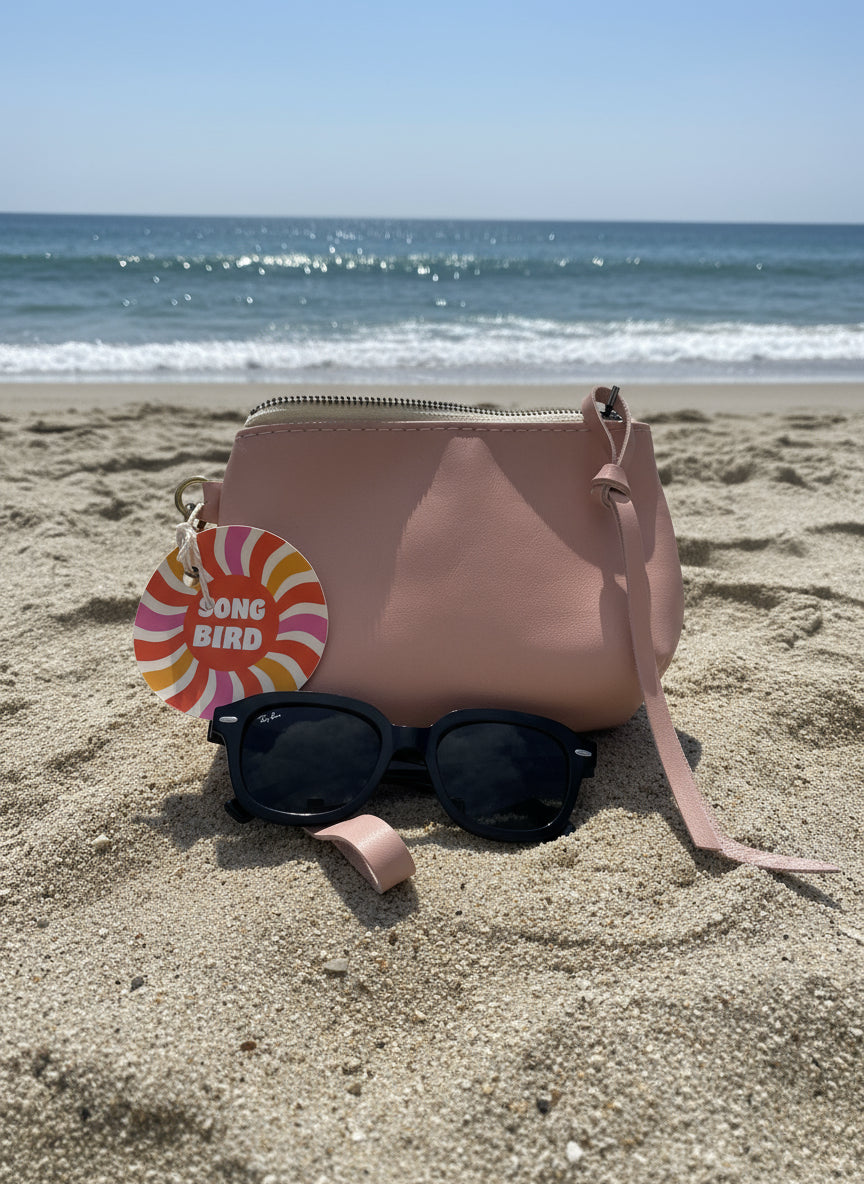 Pink handbag with sunglasses and a 'Song Bird'